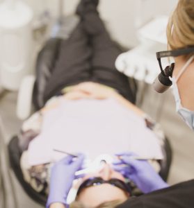 patient in dental chair as dentist works on their teeth