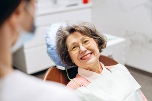 older woman in dental chair smiling at dentist